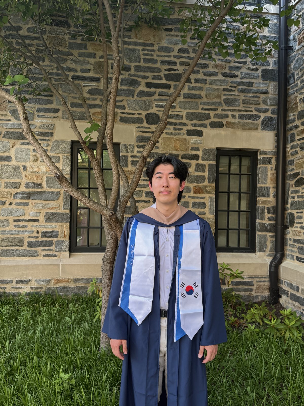Tommy at Villanova graduation, in a navy gown with a Korean flag sash